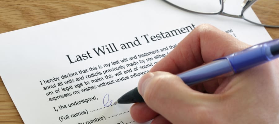 a close up shot of someone signing their name on their Last Will & Testament